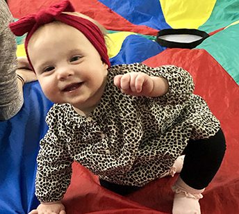 A baby girl with a red bow on her head.