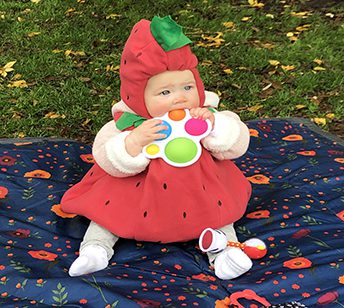 A baby dressed in costume sitting on the ground.